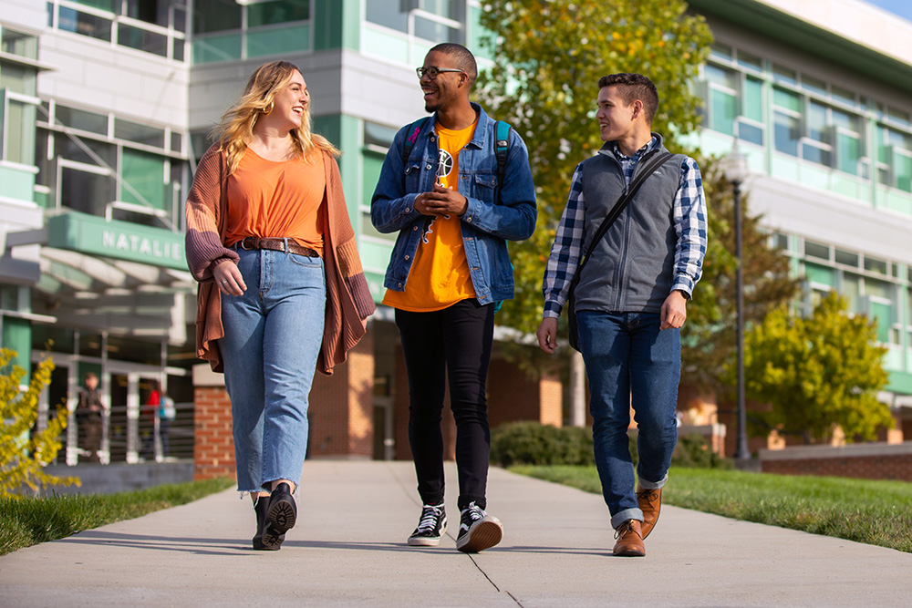 Three students walk on campus.