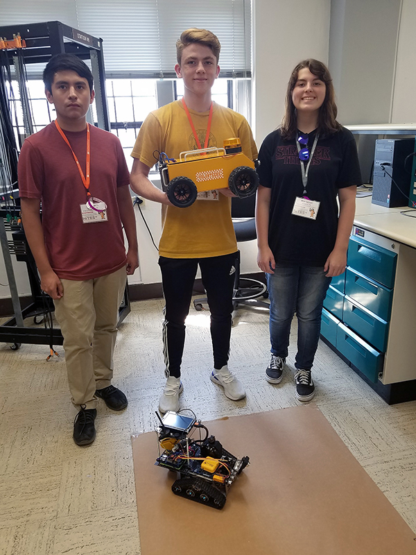 Three high school seniors with a robot.