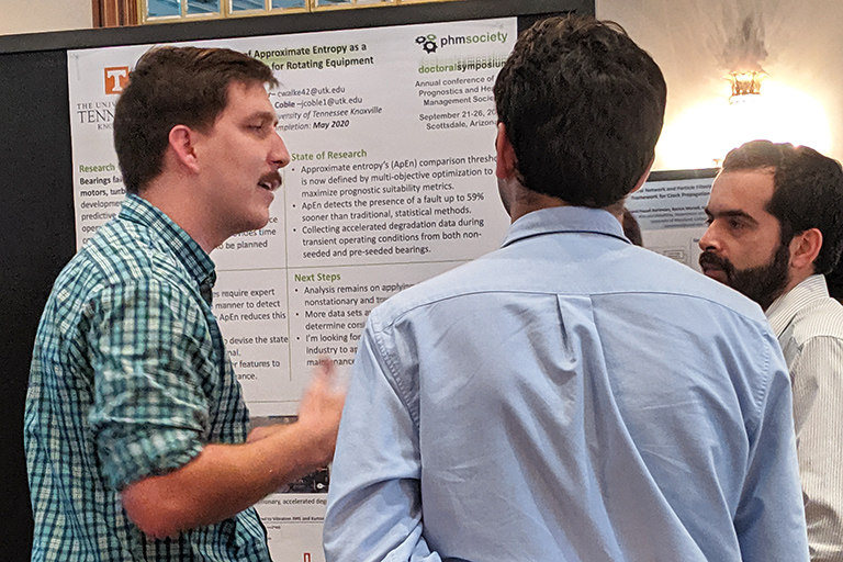 Cody Walker discusses his presentation with two conference attendees.