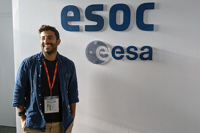 Naser Burahmah smiles in front of a sign reading "ESOC."