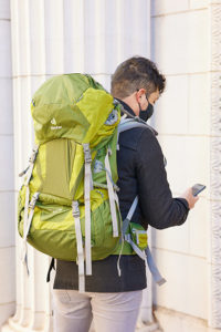 Student walks through an urban area with the detection device inside a green backpack.