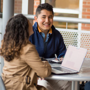 Two students sit at an exterior table.
