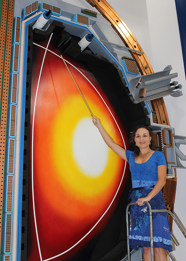 Livia Casali points at a full scale model of the cross section of the DIII-D tokamak.
