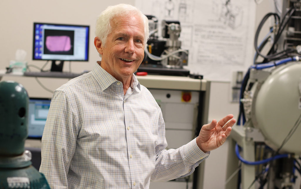 Chuck Melcher, Director of the Scintillation Materials Research Center stands in front of equipment used for research and discovery.