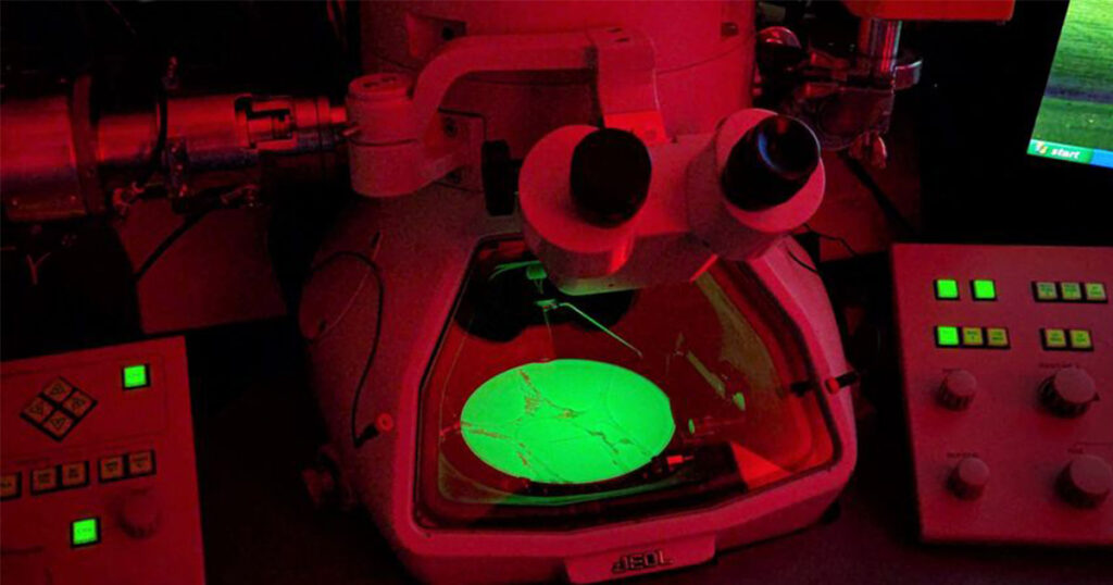 A microscope with a sample of material glowing on a slide