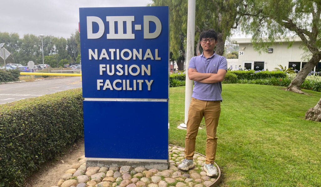 Jun Ren standing in front of DIII-D National Fusion Facility sign