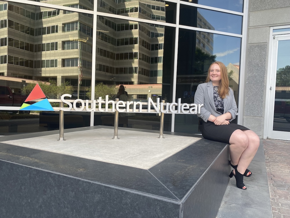 Madison Vandergriff sitting beside the southern nuclear company sign