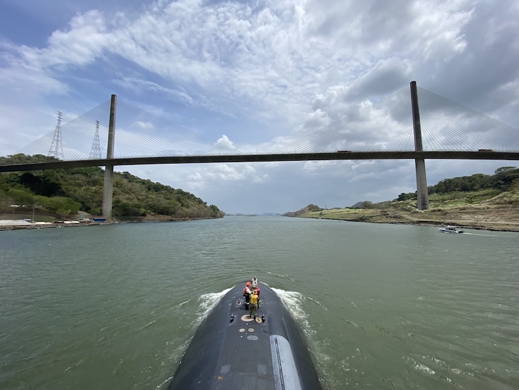 navy submarine above water going under a bridge